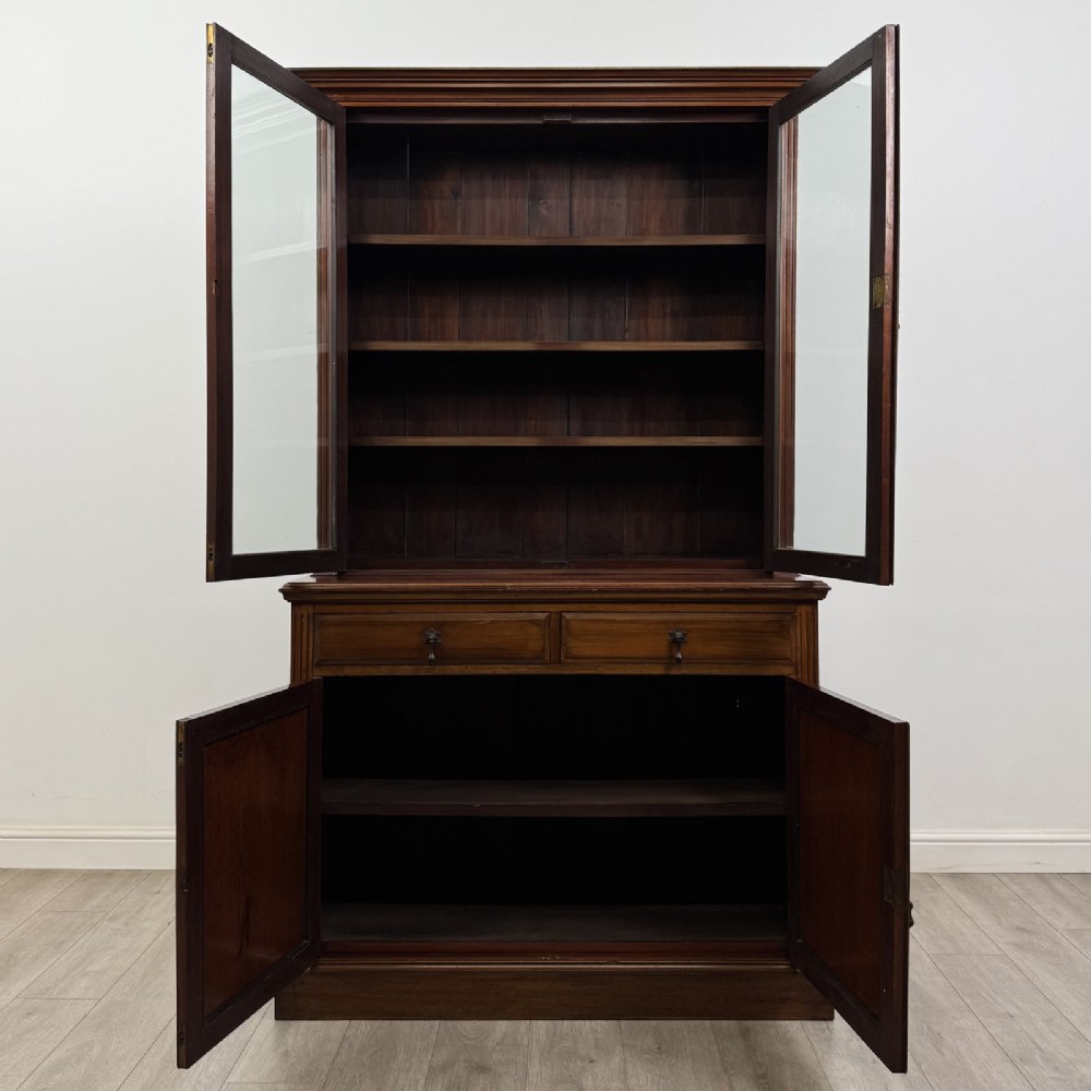 An antique Victorian mahogany glazed bookcase featuring two upper glass doors, twin frieze drawers, and lower panelled doors. View X