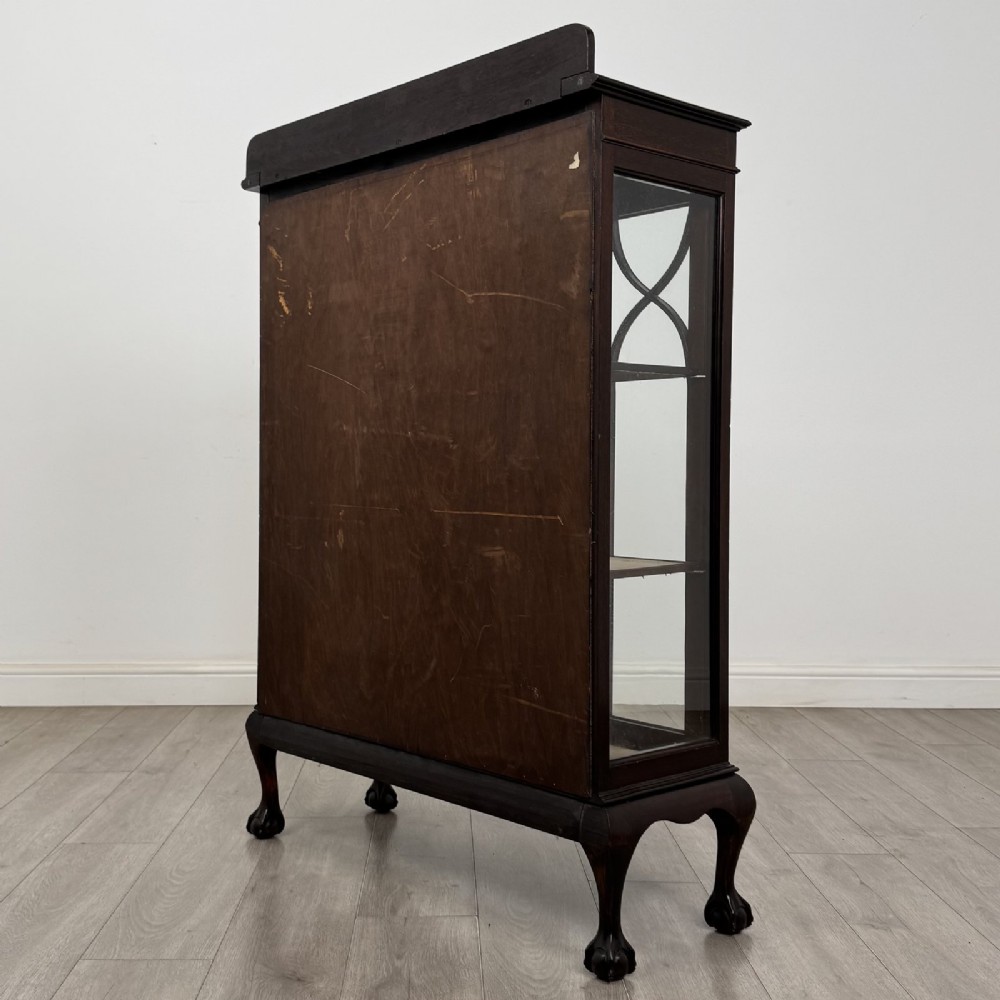 A dark mahogany display cabinet featuring two glazed doors with geometric arch bars and carved ball-and-claw feet. View VI