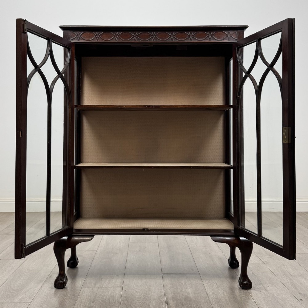 A dark mahogany display cabinet featuring two glazed doors with geometric arch bars and carved ball-and-claw feet. View IX