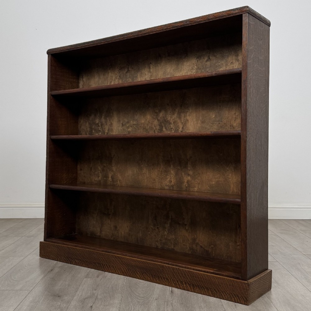 A dark oak open bookcase featuring four tier adjustable shelves and carved moulding along the top frieze. View III