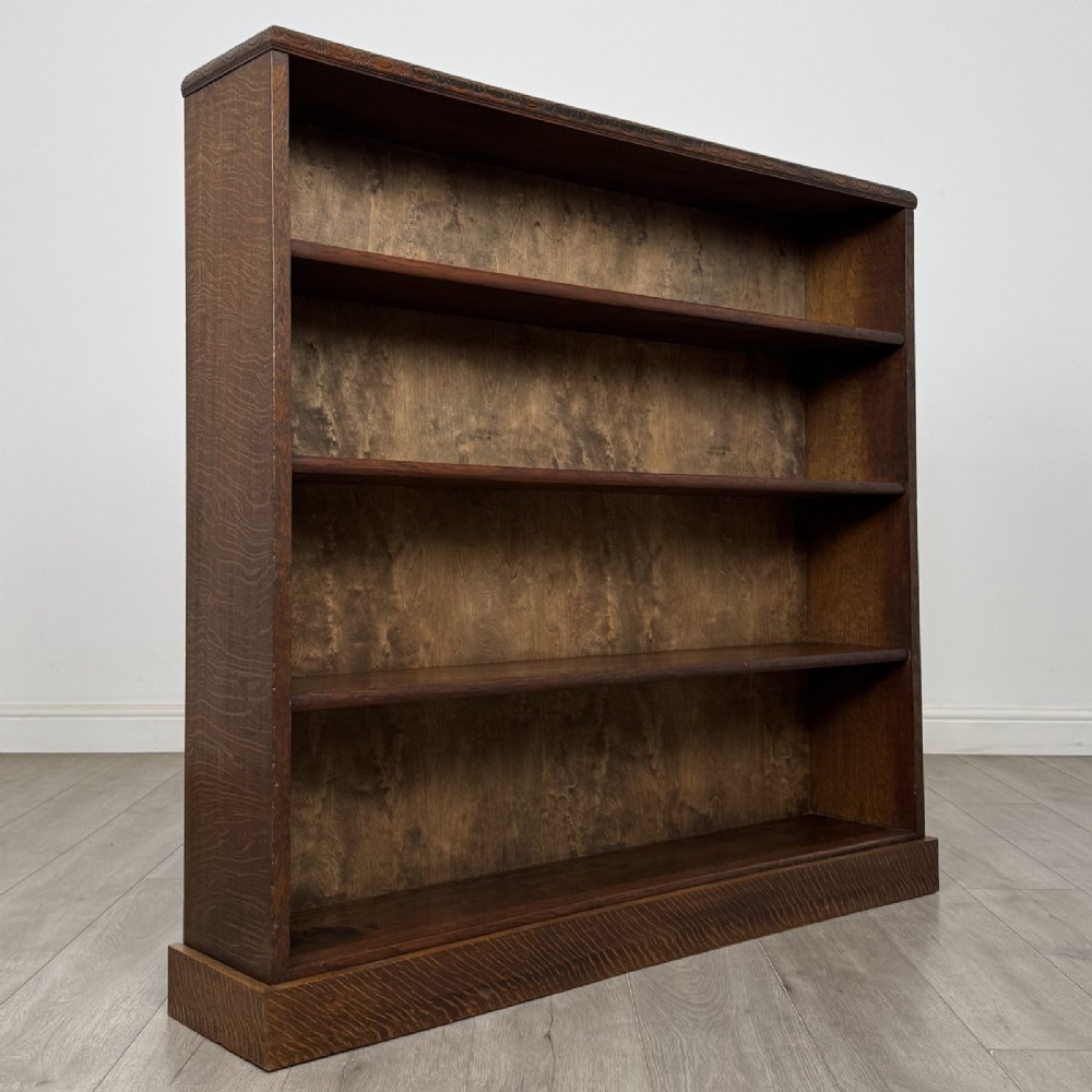 A dark oak open bookcase featuring four tier adjustable shelves and carved moulding along the top frieze. View IX