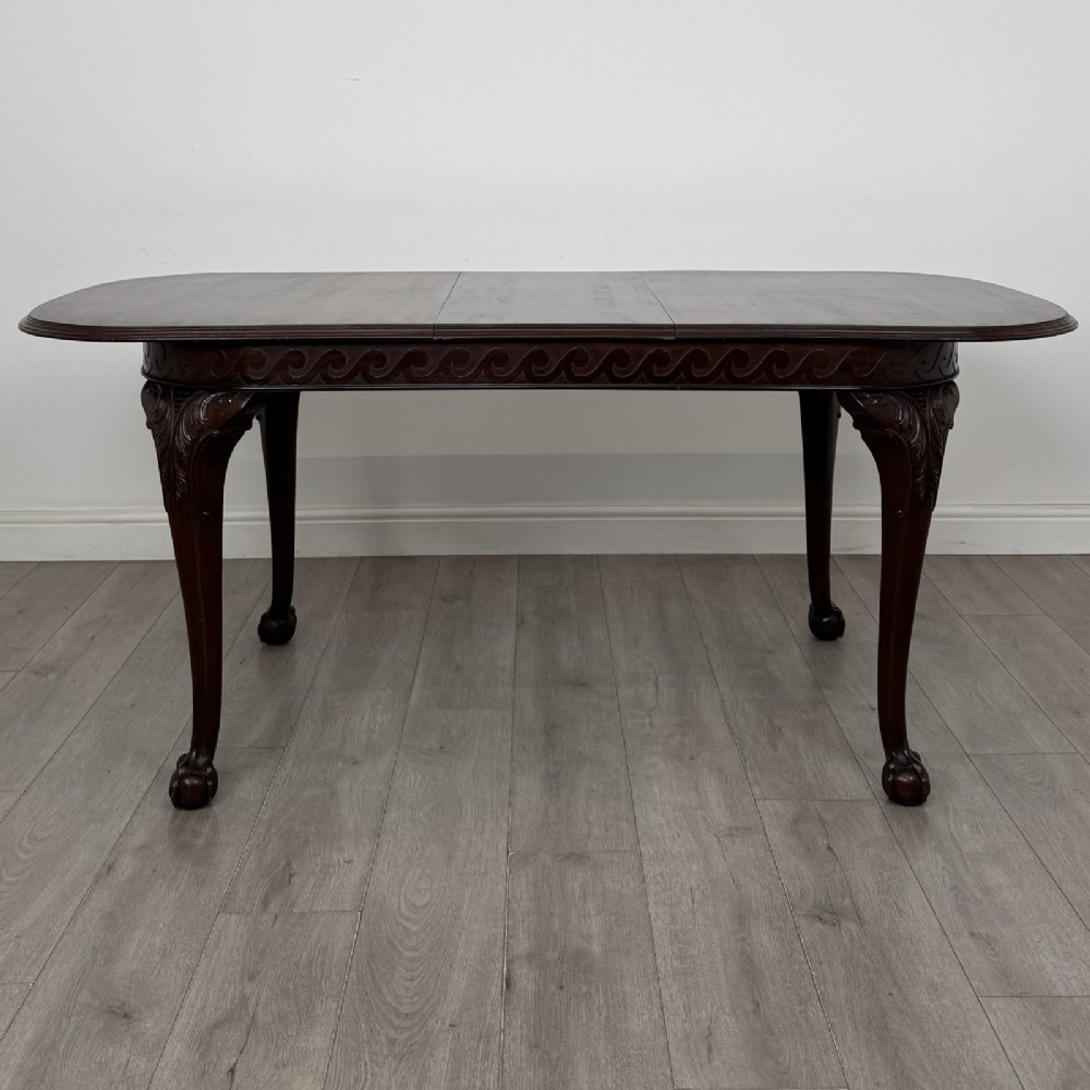 An Edwardian mahogany extending dining table featuring a carved frieze and cabriole legs terminating in ball-and-claw feet. View II