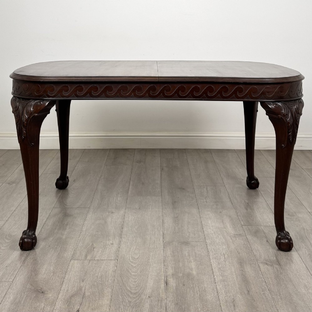 An Edwardian mahogany extending dining table featuring a carved frieze and cabriole legs terminating in ball-and-claw feet. View III