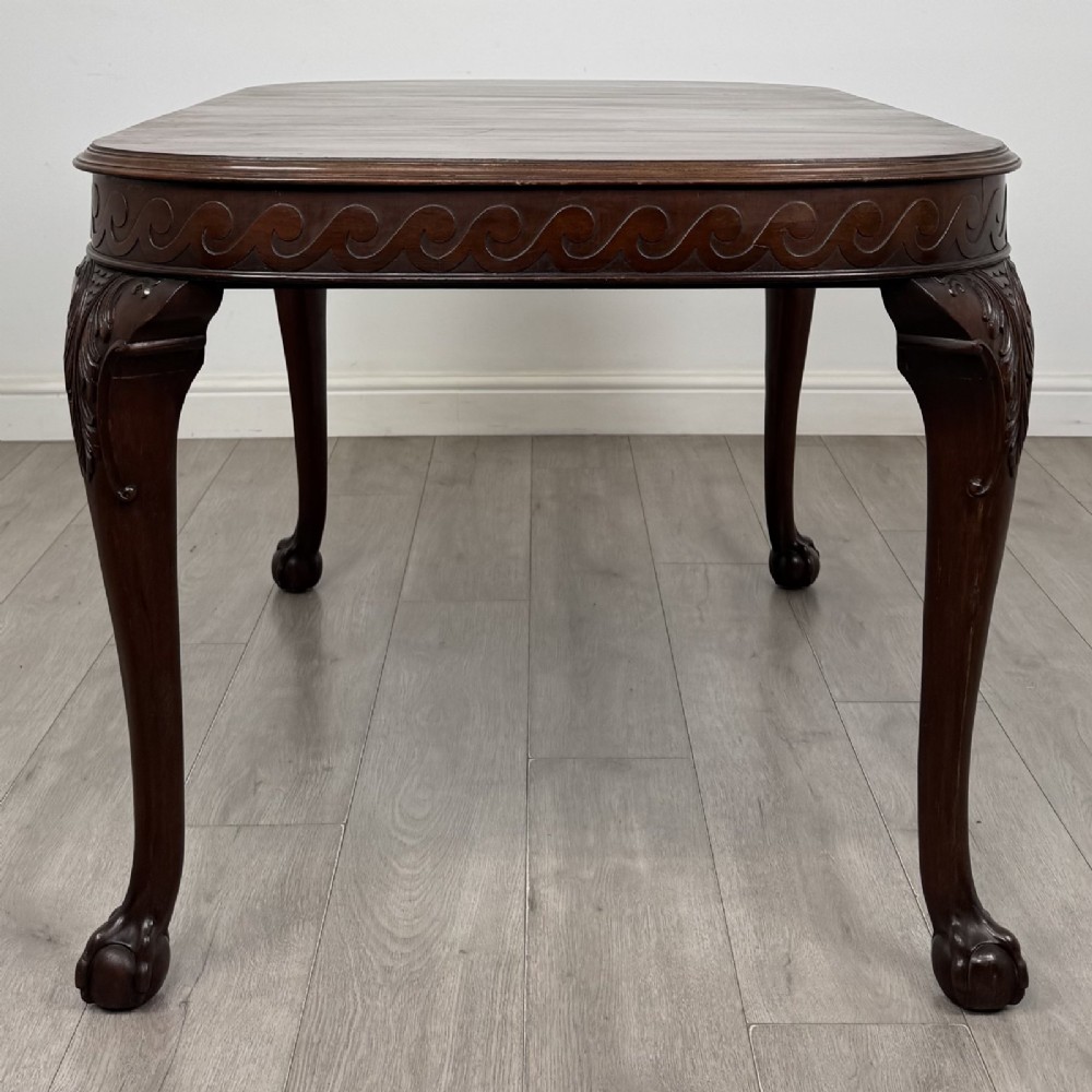 An Edwardian mahogany extending dining table featuring a carved frieze and cabriole legs terminating in ball-and-claw feet. View V