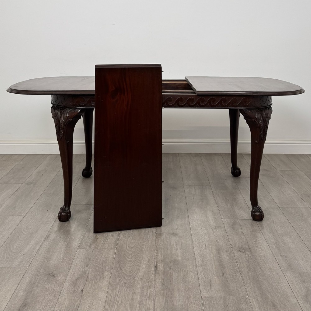 An Edwardian mahogany extending dining table featuring a carved frieze and cabriole legs terminating in ball-and-claw feet. View VII