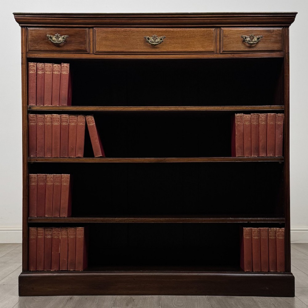 An Edwardian dark mahogany open bookcase featuring three frieze drawers with brass drop handles and three adjustable wooden shelves above a plinth base. View II