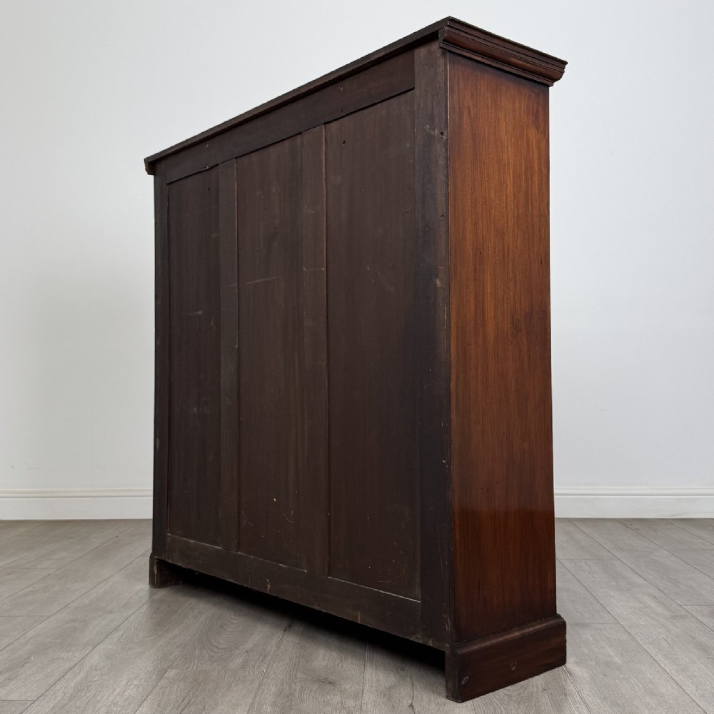 An Edwardian dark mahogany open bookcase featuring three frieze drawers with brass drop handles and three adjustable wooden shelves above a plinth base. View VII