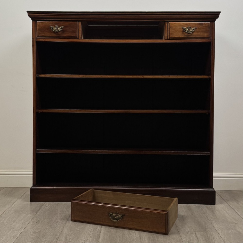 An Edwardian dark mahogany open bookcase featuring three frieze drawers with brass drop handles and three adjustable wooden shelves above a plinth base. View XI