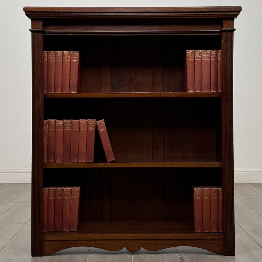 A dark brown Victorian pine open bookcase featuring adjustable shelving, reeded side pilasters, and a shaped apron at the base. View II