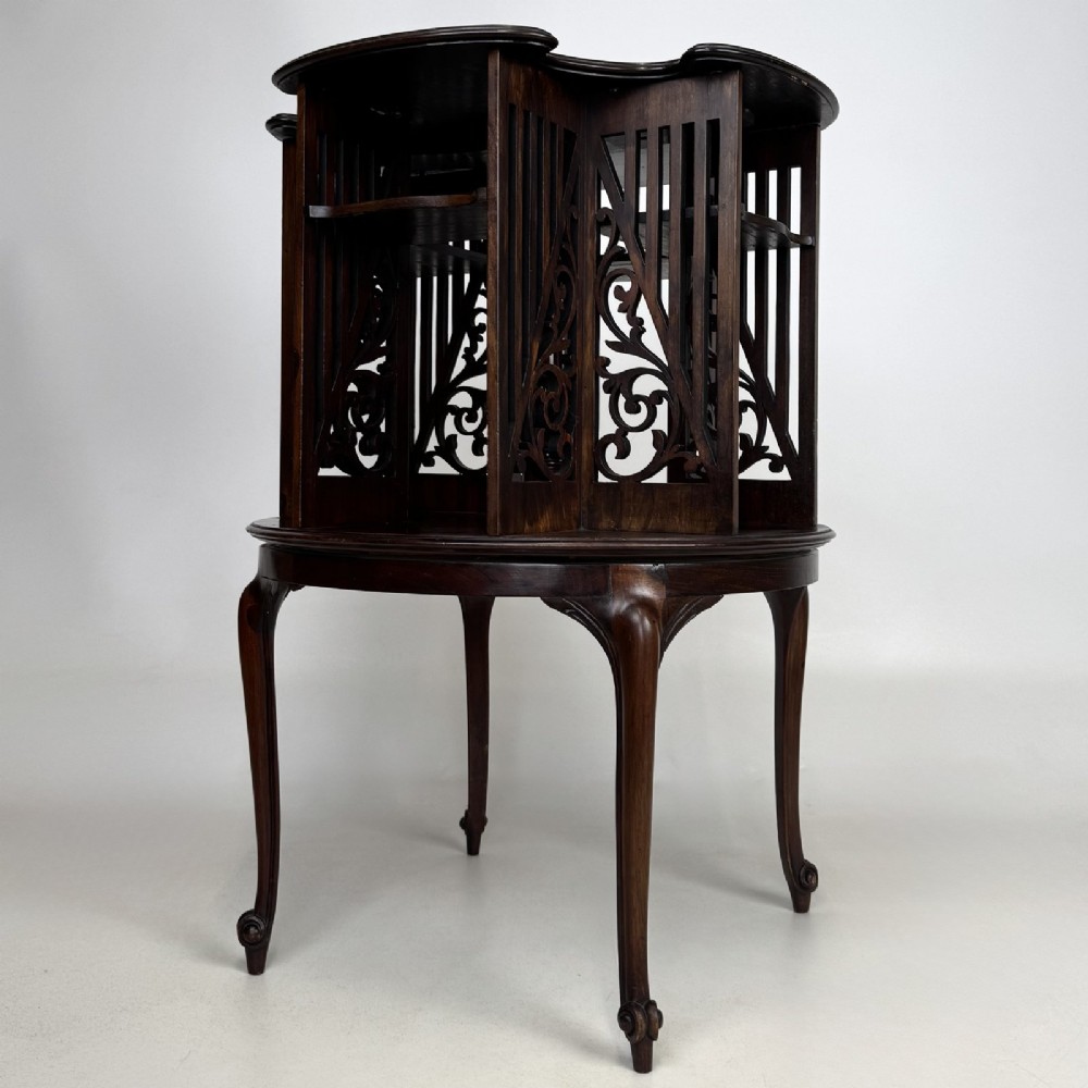 An Edwardian dark mahogany revolving bookcase with pierced foliage fretwork side panels and cabriole legs. View IV