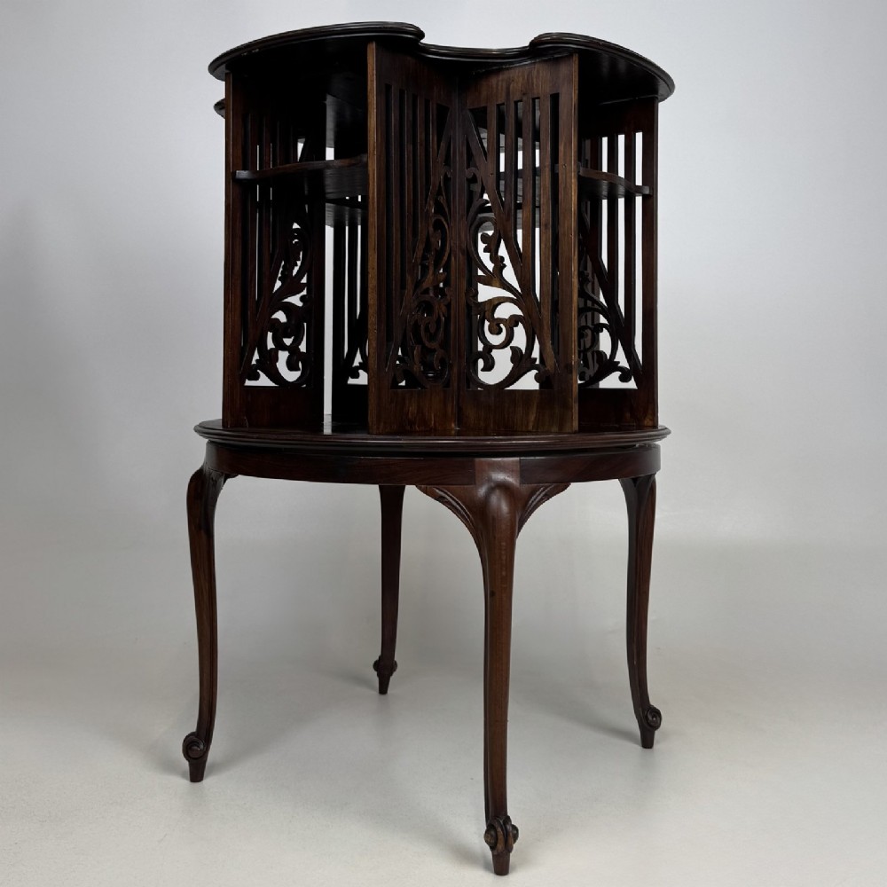 An Edwardian dark mahogany revolving bookcase with pierced foliage fretwork side panels and cabriole legs. View VI