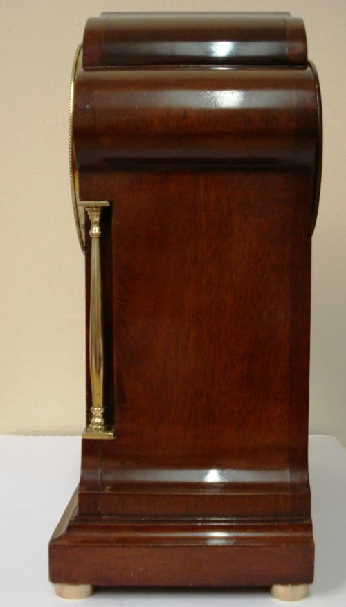fig 1. An antique inlaid mahogany mantel clock with brass side columns and an enamel dial featuring a gilt central motif.