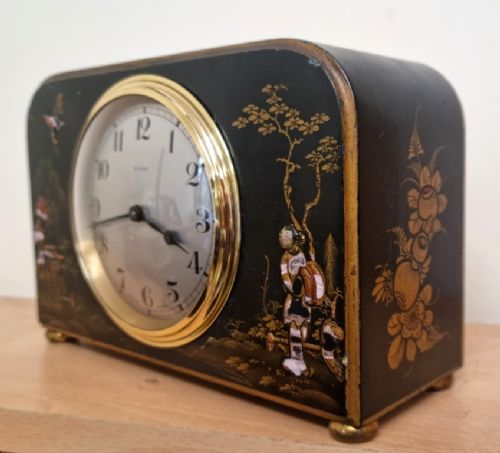fig 2. A rectangular black lacquered French mantel clock featuring gold chinoiserie decoration, a brass bezel, and a white dial displaying Arabic numerals.