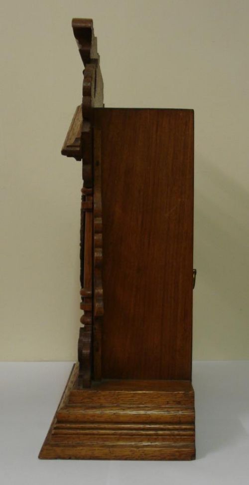 fig 1. A carved oak Ansonia 8-day mantel clock featuring an architectural pediment, side columns, and a white dial with Arabic numerals.