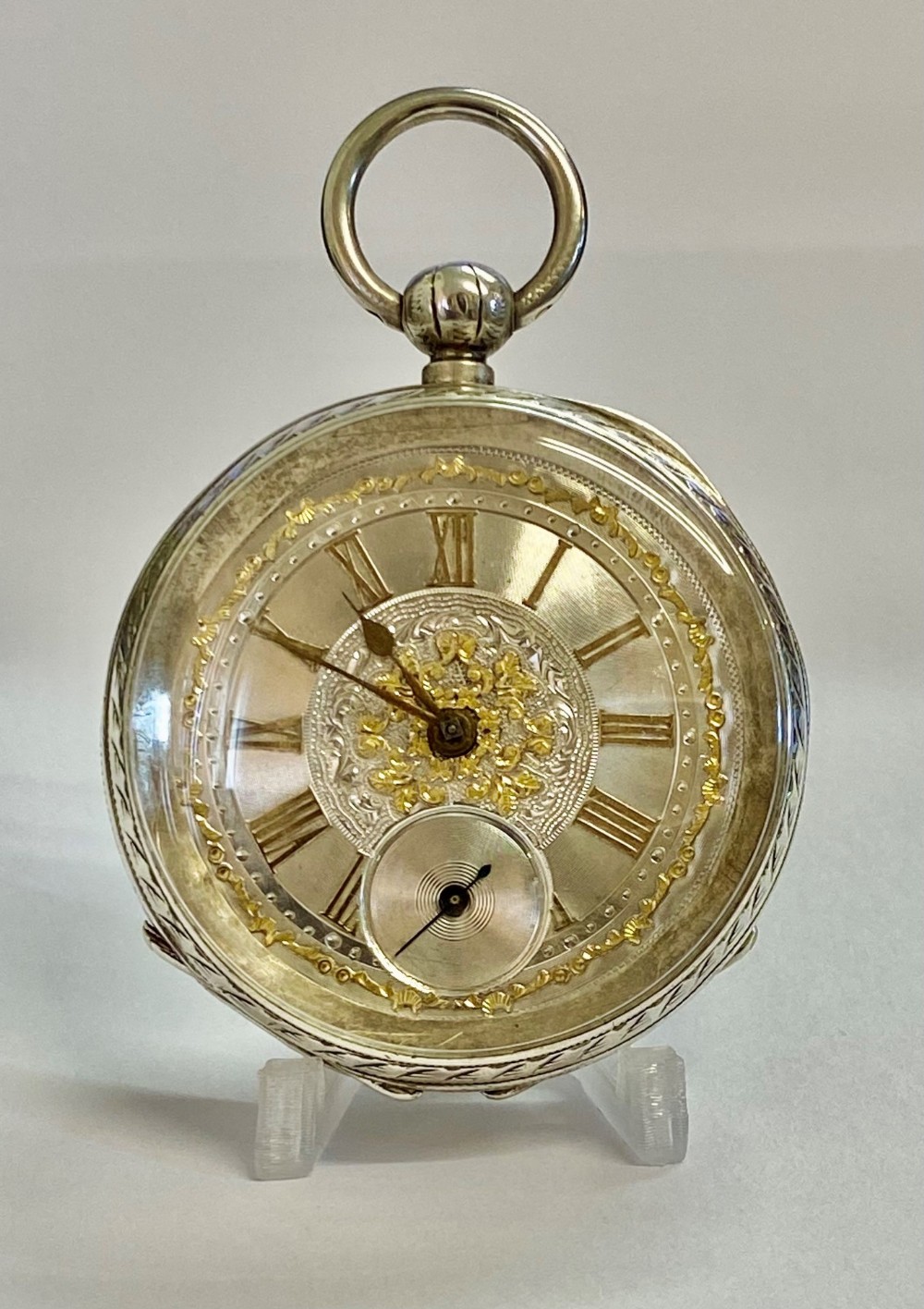 A late nineteenth-century Swiss open-face pocket watch with an engraved silver dial, gilded Roman numerals, and a subsidiary seconds dial.