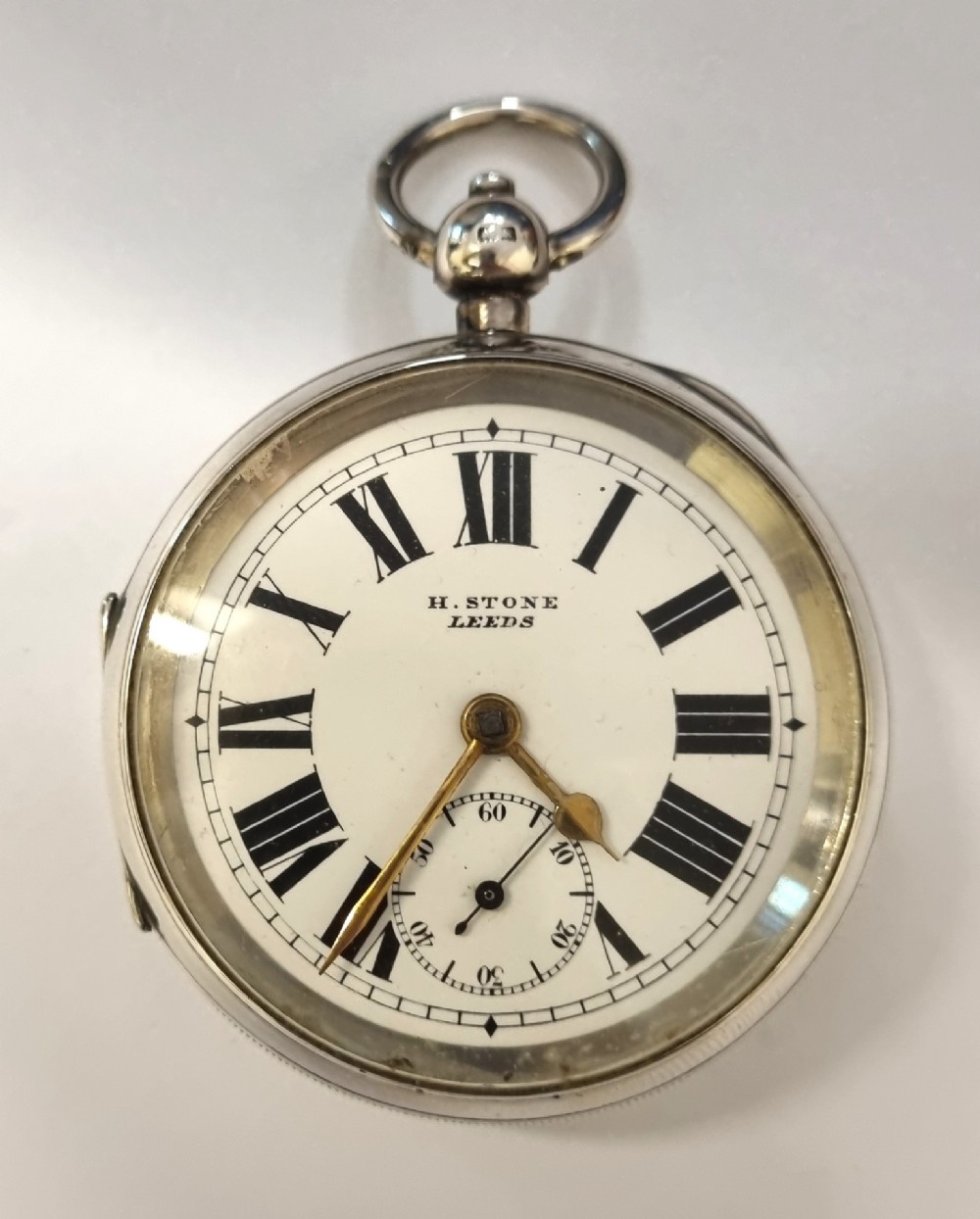 An antique English open-face pocket watch featuring a sterling silver case, white enamel dial with black Roman numerals, and a subsidiary seconds dial.