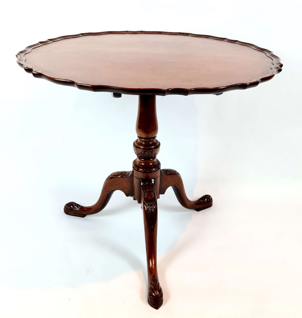 A 19th-century mahogany tripod table with a piecrust scalloped top, turned central column, and three carved cabriole legs.