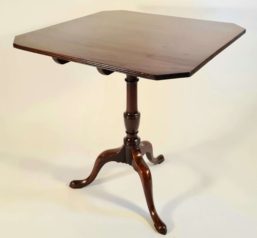 A George III mahogany tripod supper table featuring a canted tilt top, turned column pedestal, and three cabriole legs.