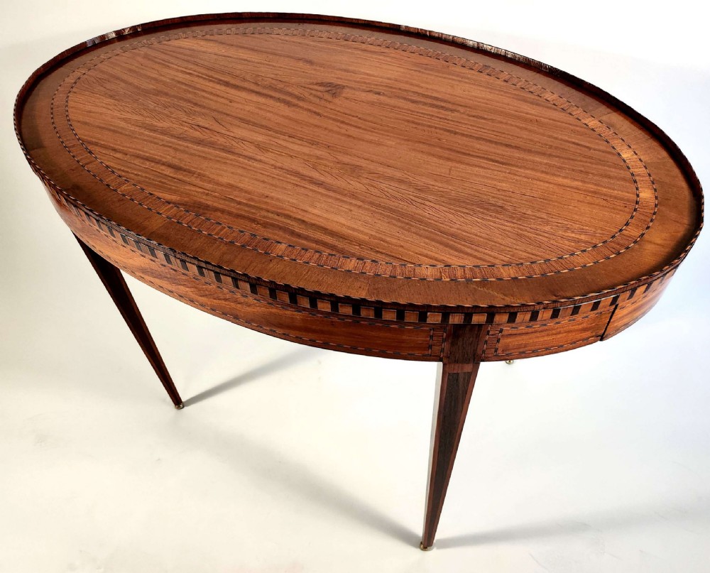 An 18th-century Dutch oval satinwood side table with inlaid geometric banding around the rim and apron, supported by four tapered square legs with brass feet. View II