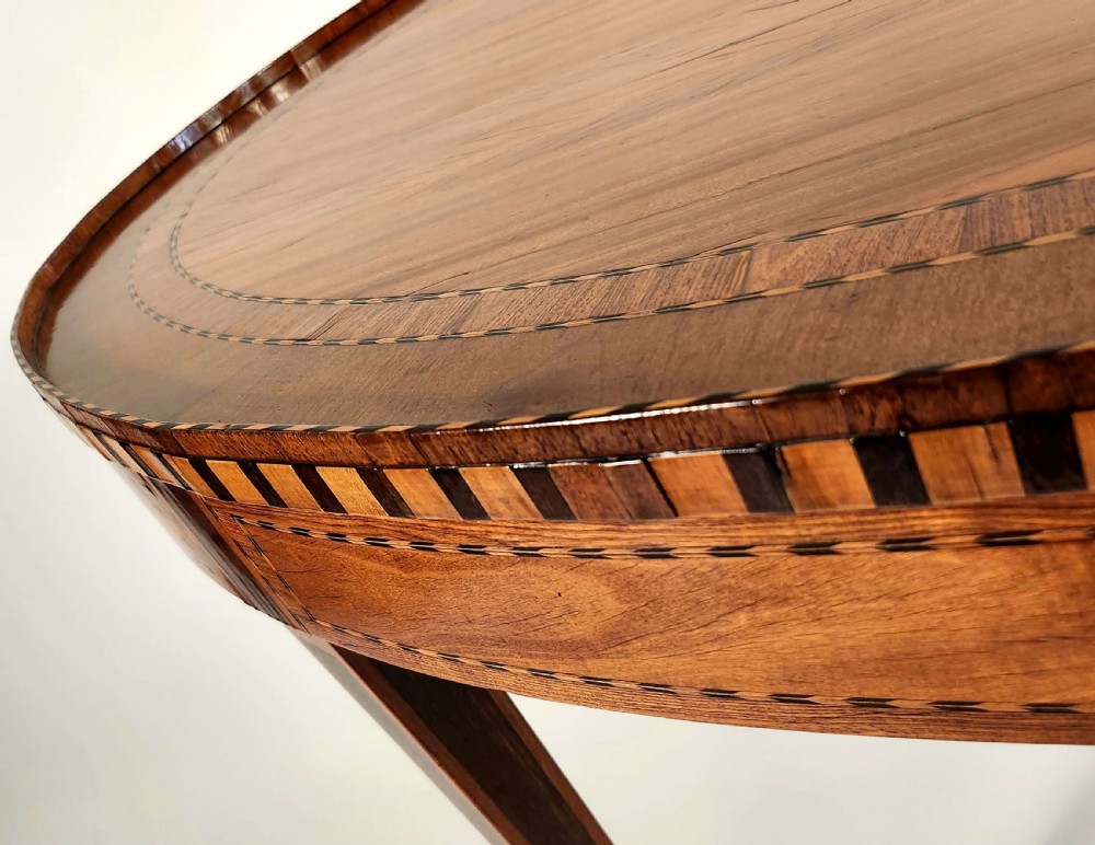 An 18th-century Dutch oval satinwood side table with inlaid geometric banding around the rim and apron, supported by four tapered square legs with brass feet. View V