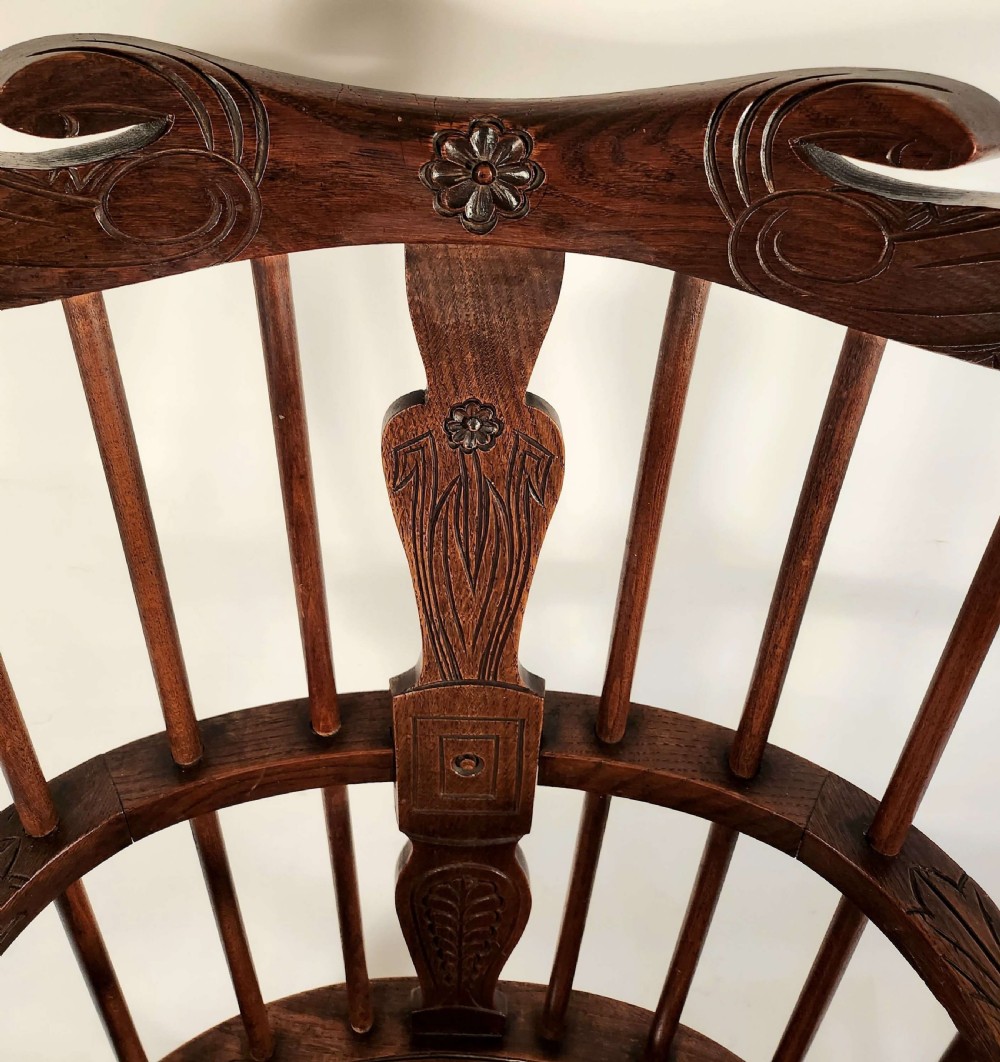 A pair of 19th-century carved oak Windsor armchairs featuring spindle backrests, carved crest rails, and relief basket motifs carved into the seats. View II