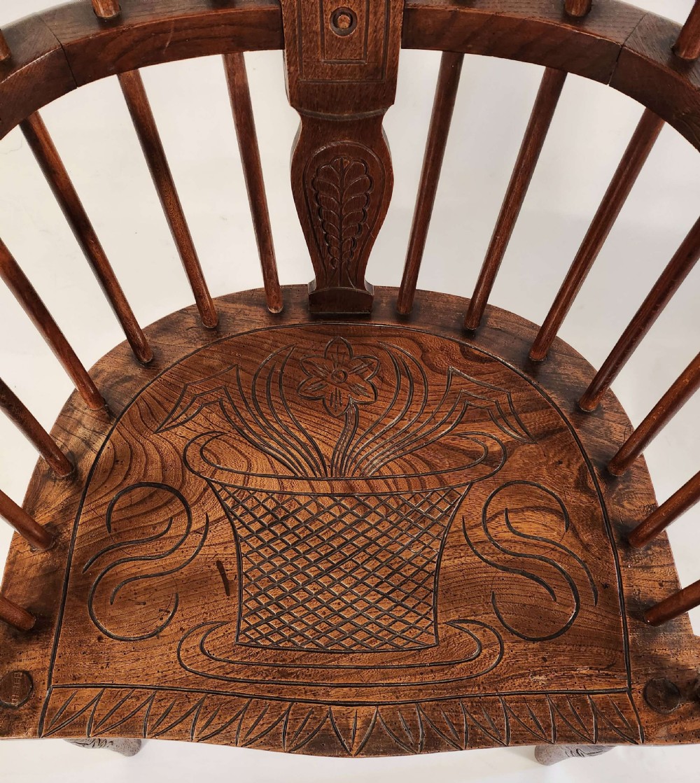 A pair of 19th-century carved oak Windsor armchairs featuring spindle backrests, carved crest rails, and relief basket motifs carved into the seats. View III
