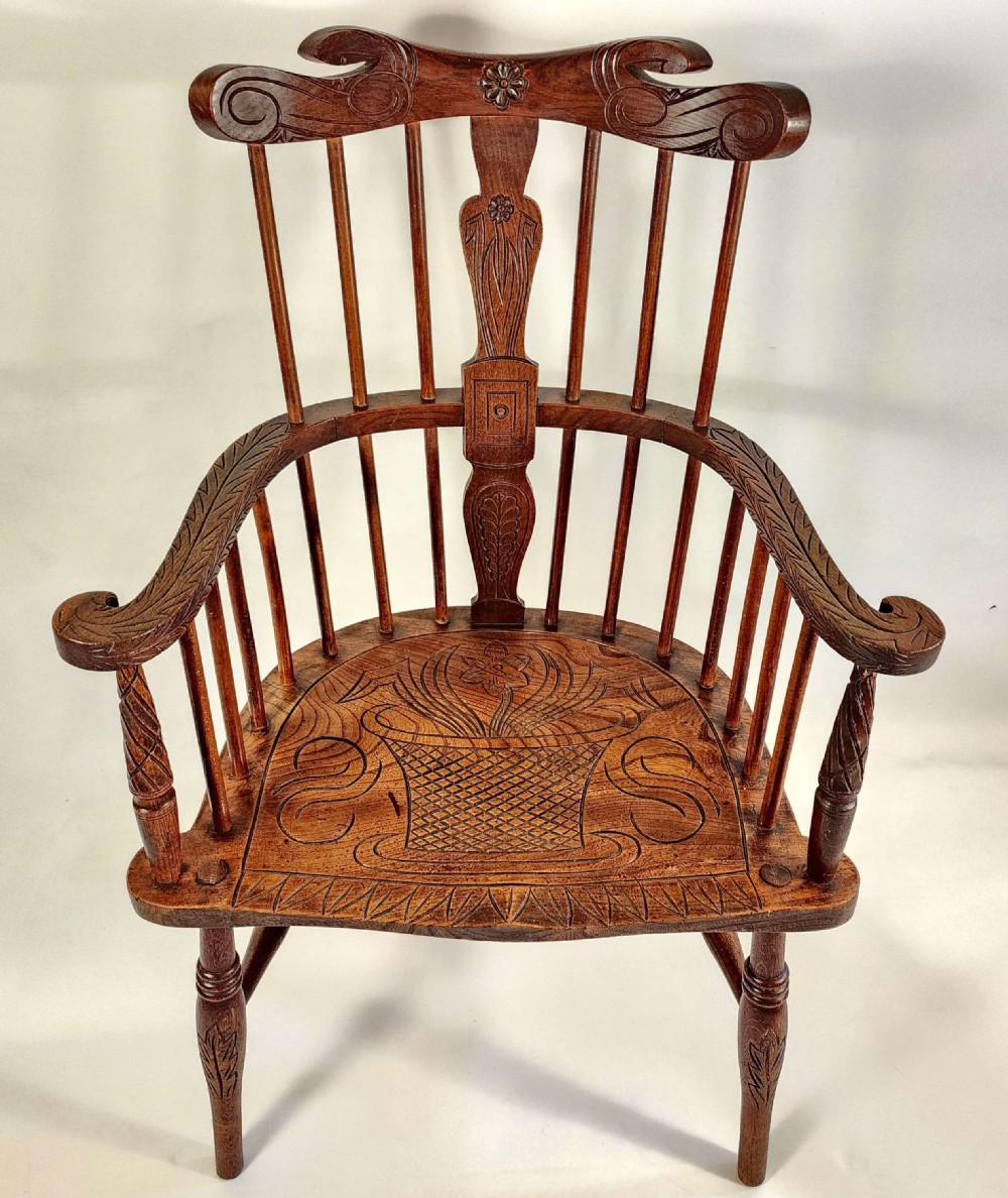 A pair of 19th-century carved oak Windsor armchairs featuring spindle backrests, carved crest rails, and relief basket motifs carved into the seats. View IV
