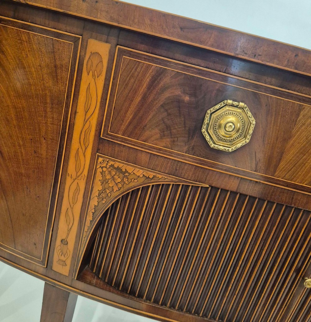 A George III mahogany bow-fronted sideboard featuring flame mahogany drawer fronts, boxwood inlay, and tapered square legs. View IV