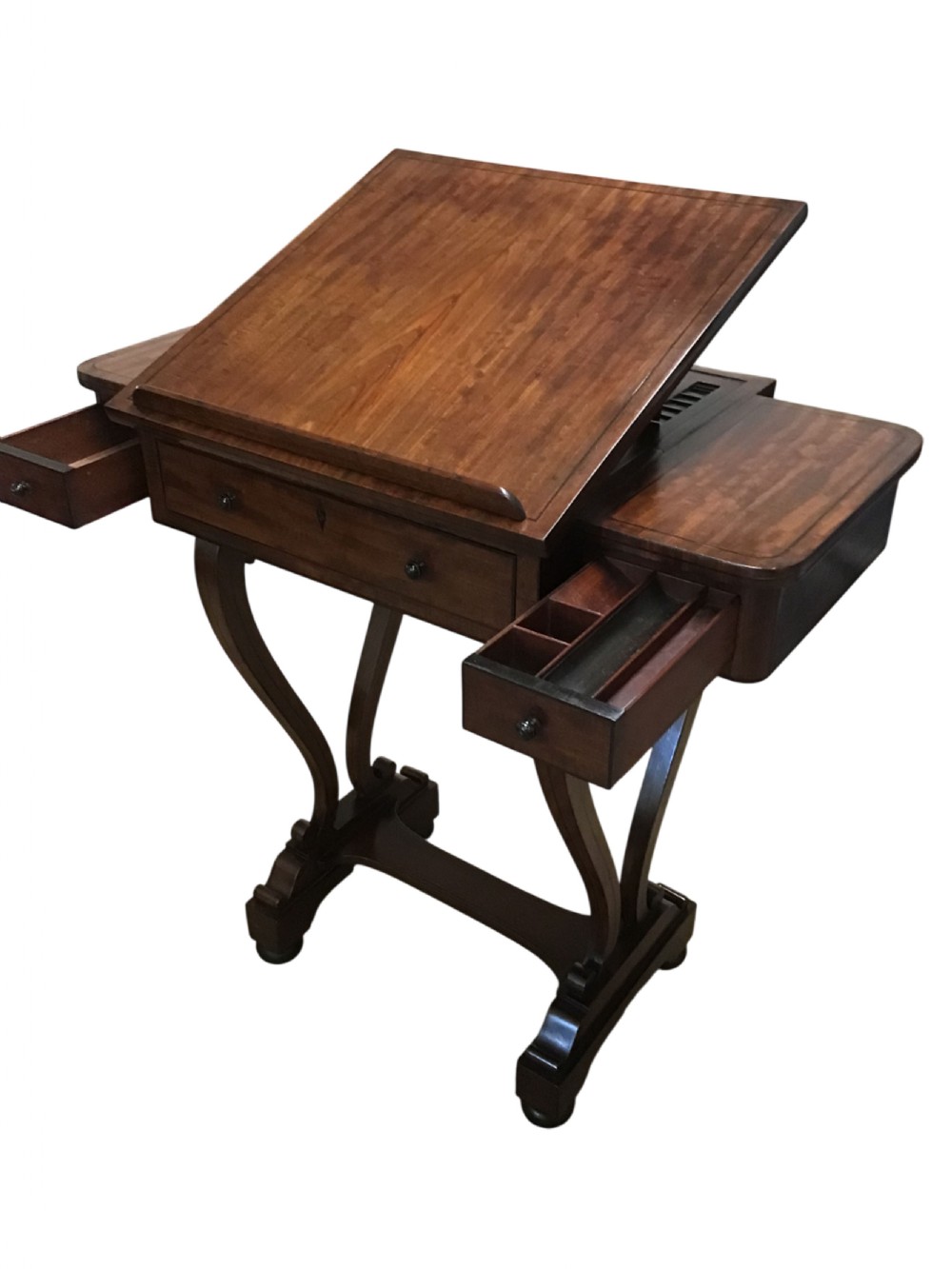 An antique Regency mahogany sofa table featuring two extending side slides, ebony stringing details, drawer knobs, and curved pedestal legs on castors. View II