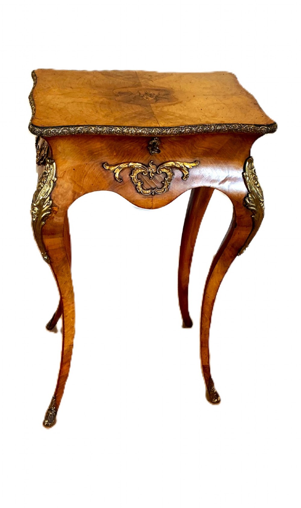 A 19th-century French walnut occasional table featuring cabriole legs, decorative gilt-bronze mounts, marquetry inlay on the top, and a moulded metal rim.