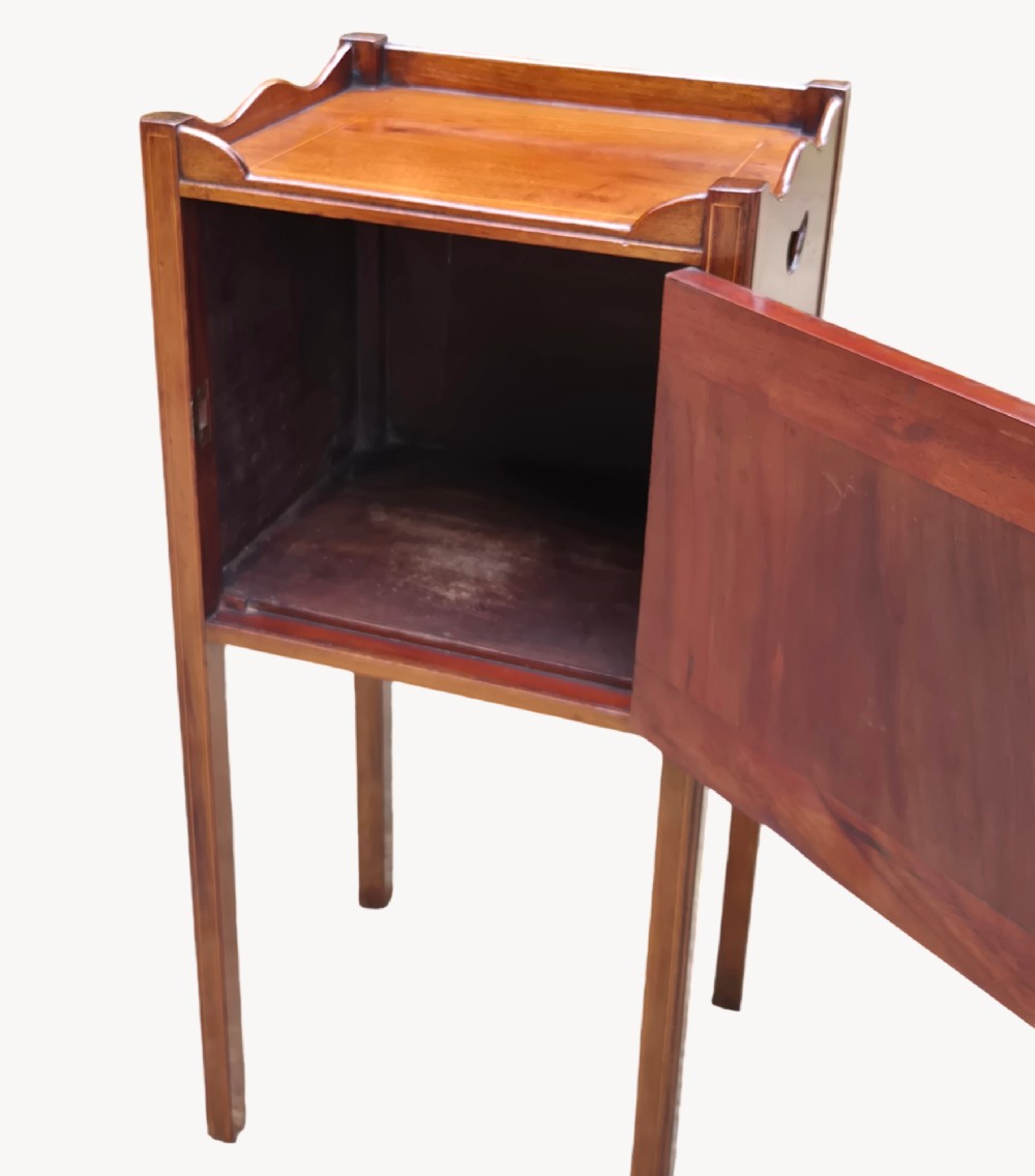 An early nineteenth-century mahogany bedside cupboard featuring a gallery tray top with handles, satinwood inlay, a single door with a brass turn handle, and square tapered legs. View II