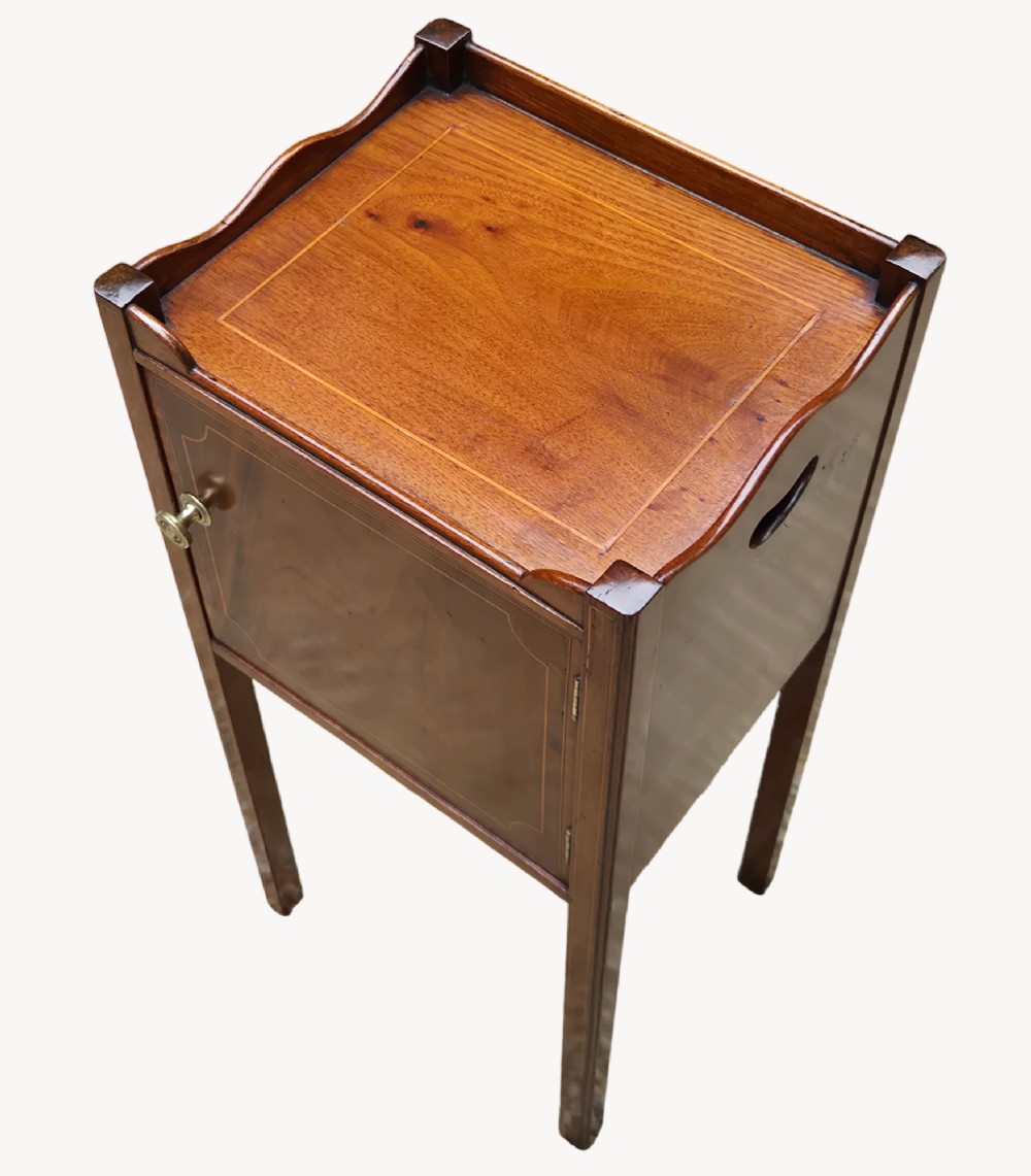 An early nineteenth-century mahogany bedside cupboard featuring a gallery tray top with handles, satinwood inlay, a single door with a brass turn handle, and square tapered legs. View III