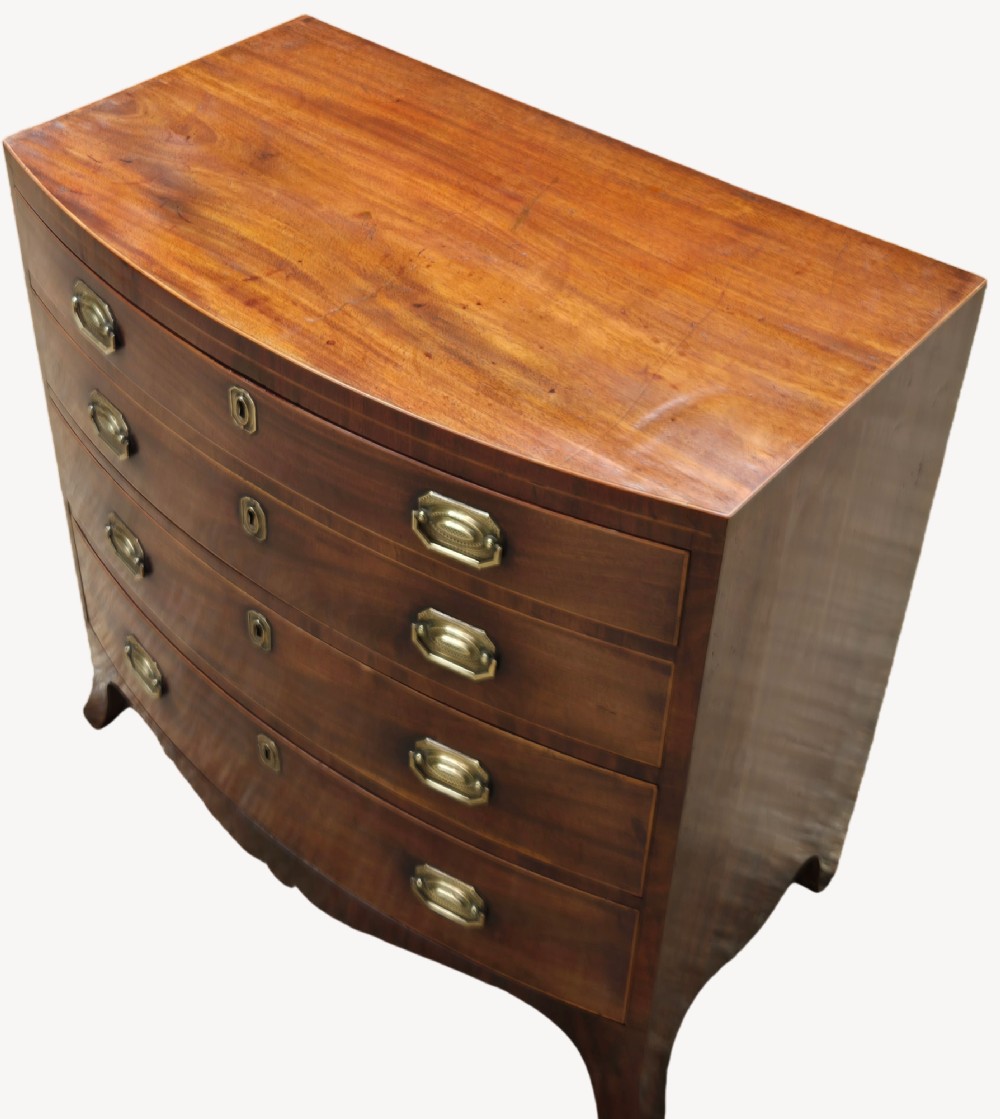 An antique mahogany bowfront chest of four graduated drawers featuring brass drop handles and splayed bracket feet. View II
