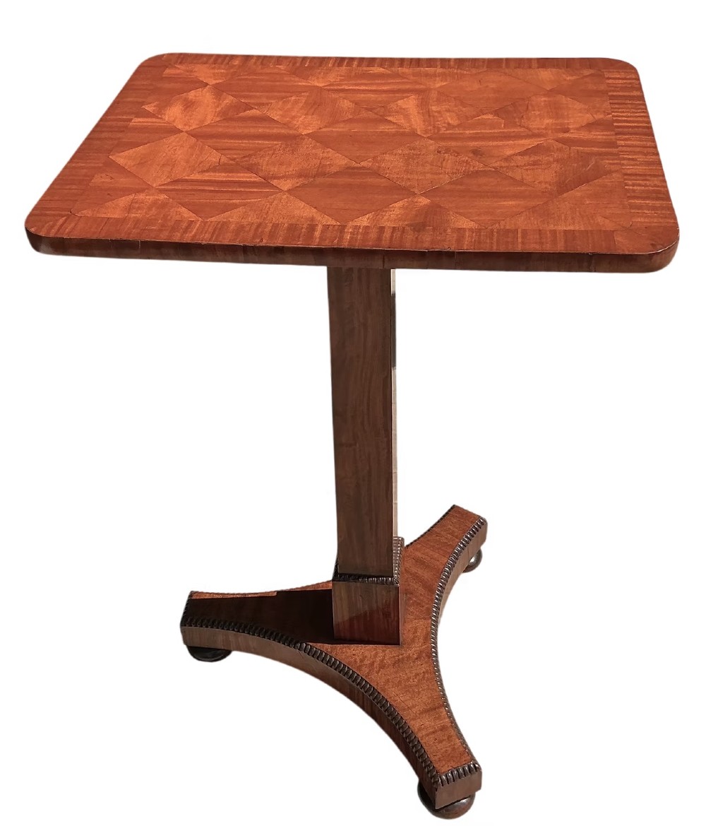 A Late Regency mahogany occasional table featuring a square parquetry top resting on a central column and a triform base.