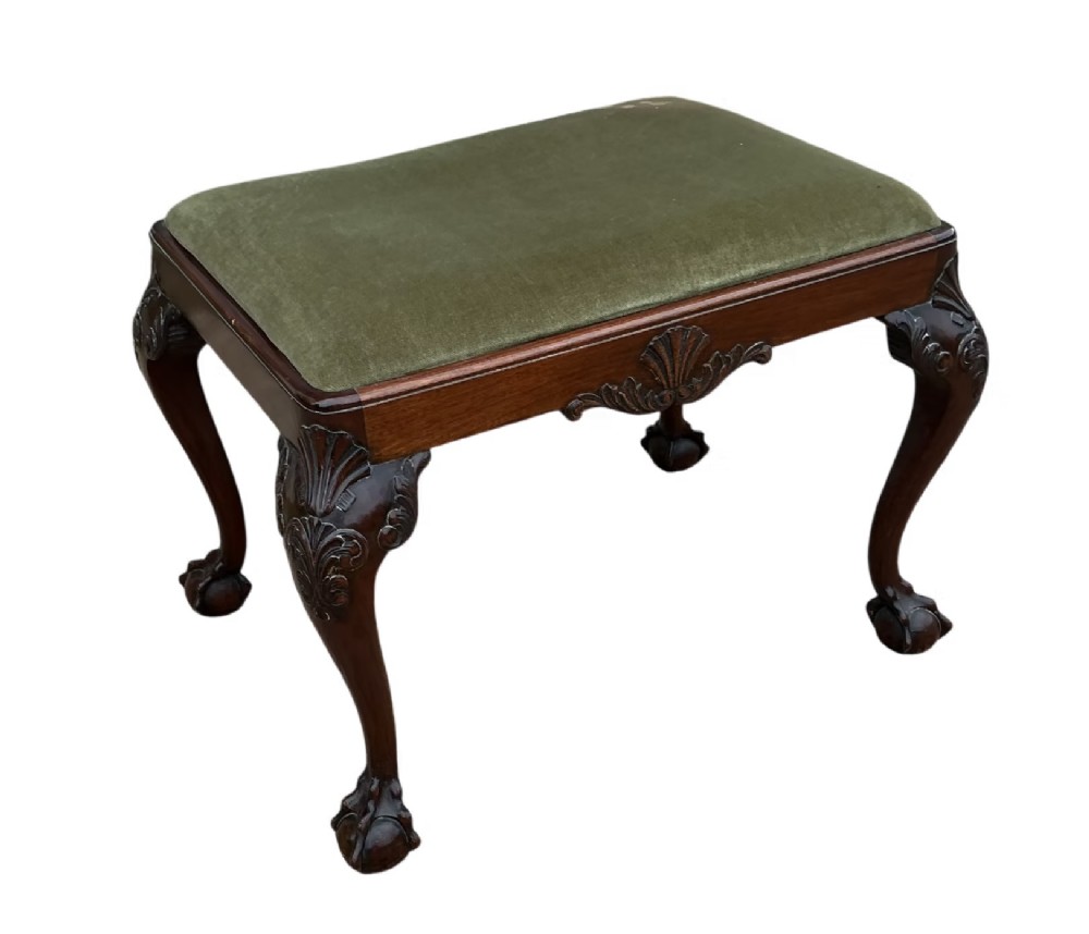 A Chippendale style mahogany stool featuring an olive green velvet upholstered seat, carved cabriole legs, and ball-and-claw feet.