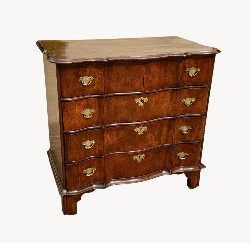 A mid-18th-century Dutch chest of drawers in warm brown burr walnut veneer with a shaped front and brass drop handles.