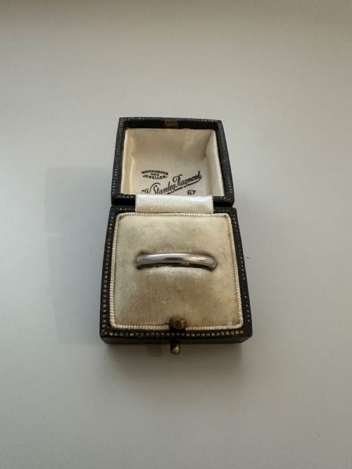 fig 1. A plain platinum wedding band displayed inside an open vintage velvet-lined leather ring box.