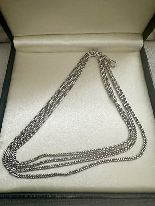 fig 1. A long, finely linked Victorian sterling silver guard chain featuring an attached swivel clasp, shown coiled on a flat surface.