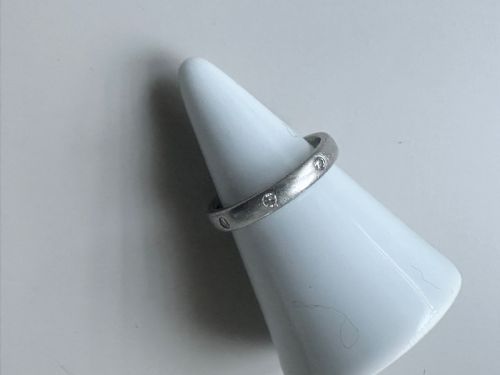 fig 1. A platinum ring band inset with round diamonds sitting inside a fitted velvet presentation box.