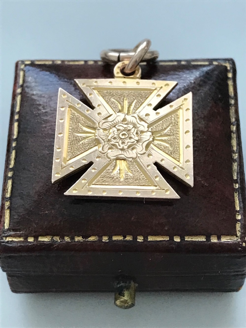 A 9ct yellow gold Maltese cross pendant featuring engraved geometric patterns, a central Tudor rose motif, and a top suspension ring. View II