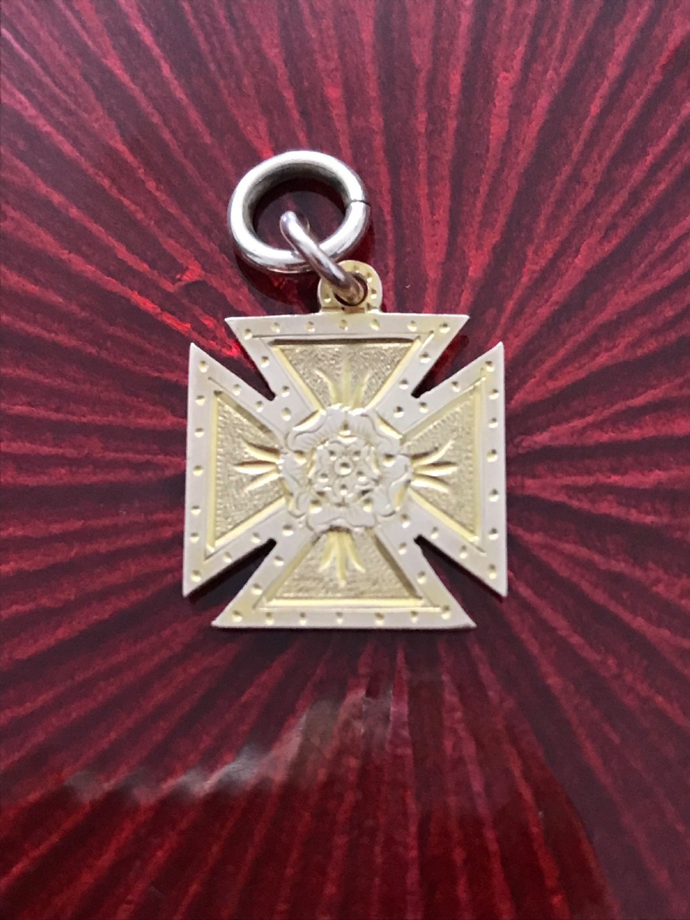 A 9ct yellow gold Maltese cross pendant featuring engraved geometric patterns, a central Tudor rose motif, and a top suspension ring. View V