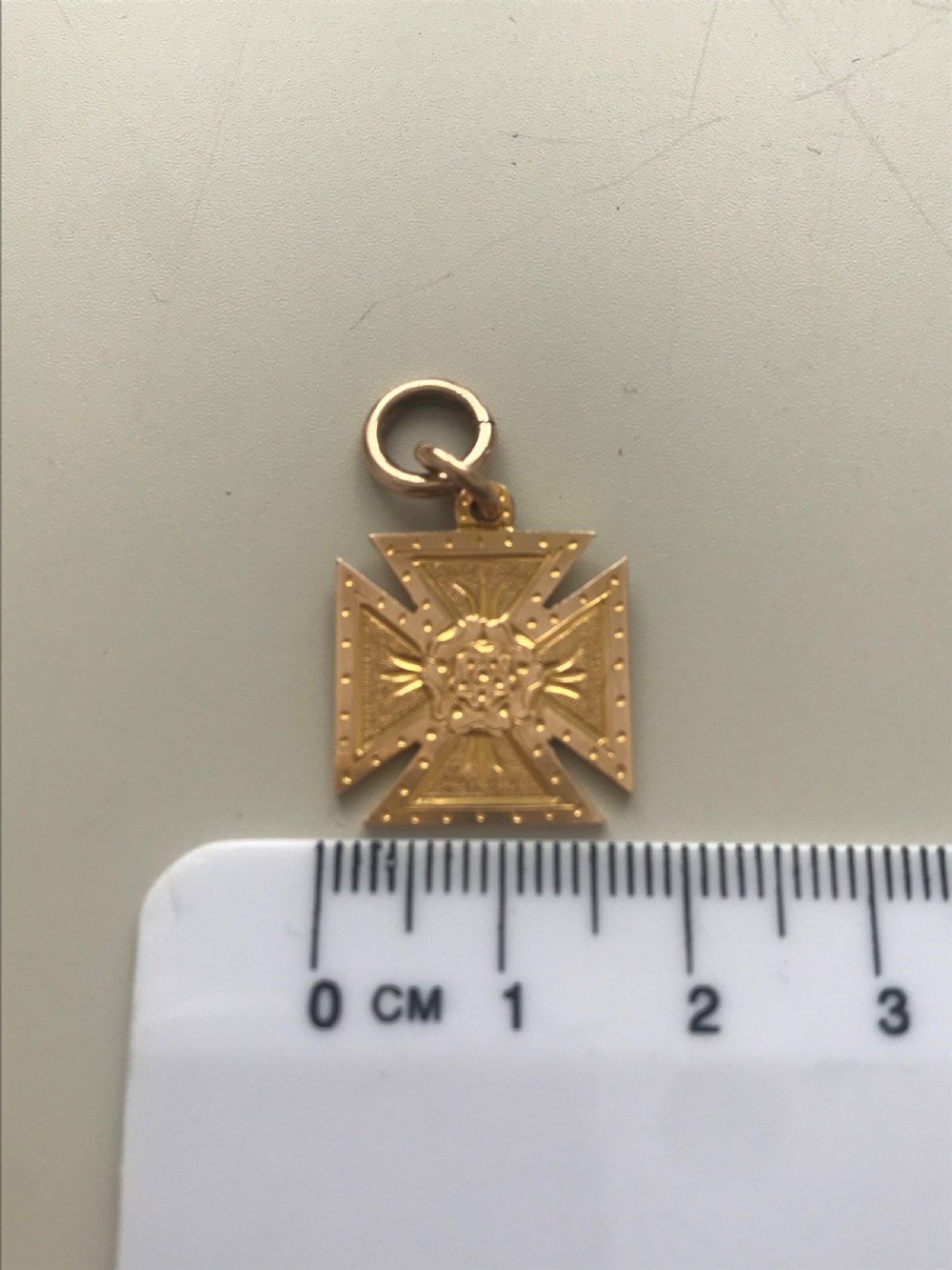 A 9ct yellow gold Maltese cross pendant featuring engraved geometric patterns, a central Tudor rose motif, and a top suspension ring. View VI