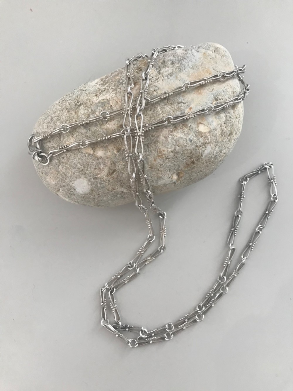 A long vintage silver chain featuring decorative fancy links with subtle beaded wire details.