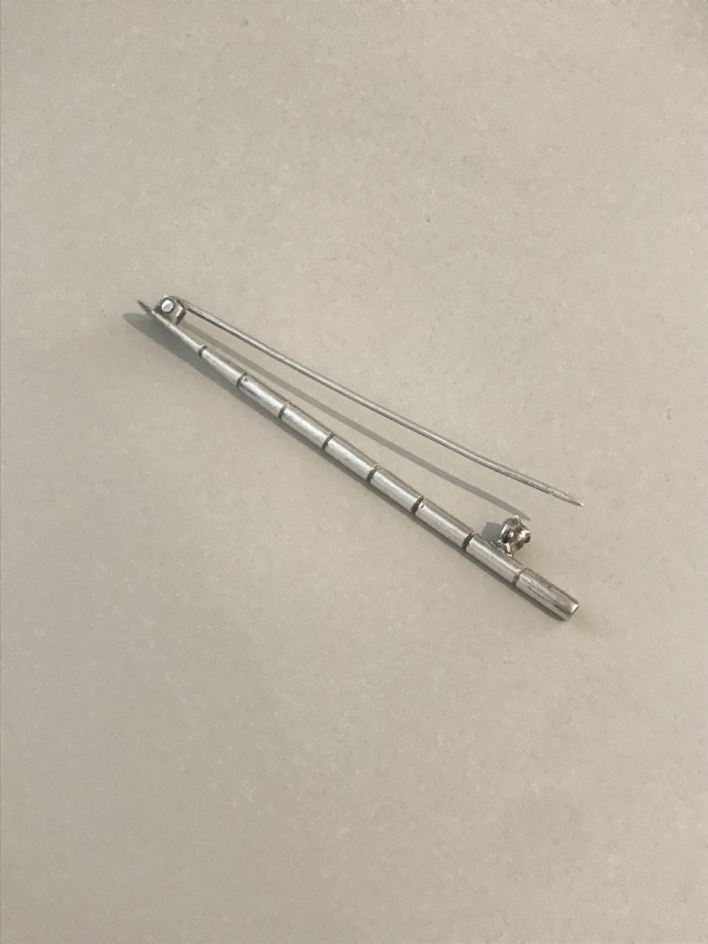 A silver brooch styled in the form of a rowing oar with a flat blade and segmented shaft. View III