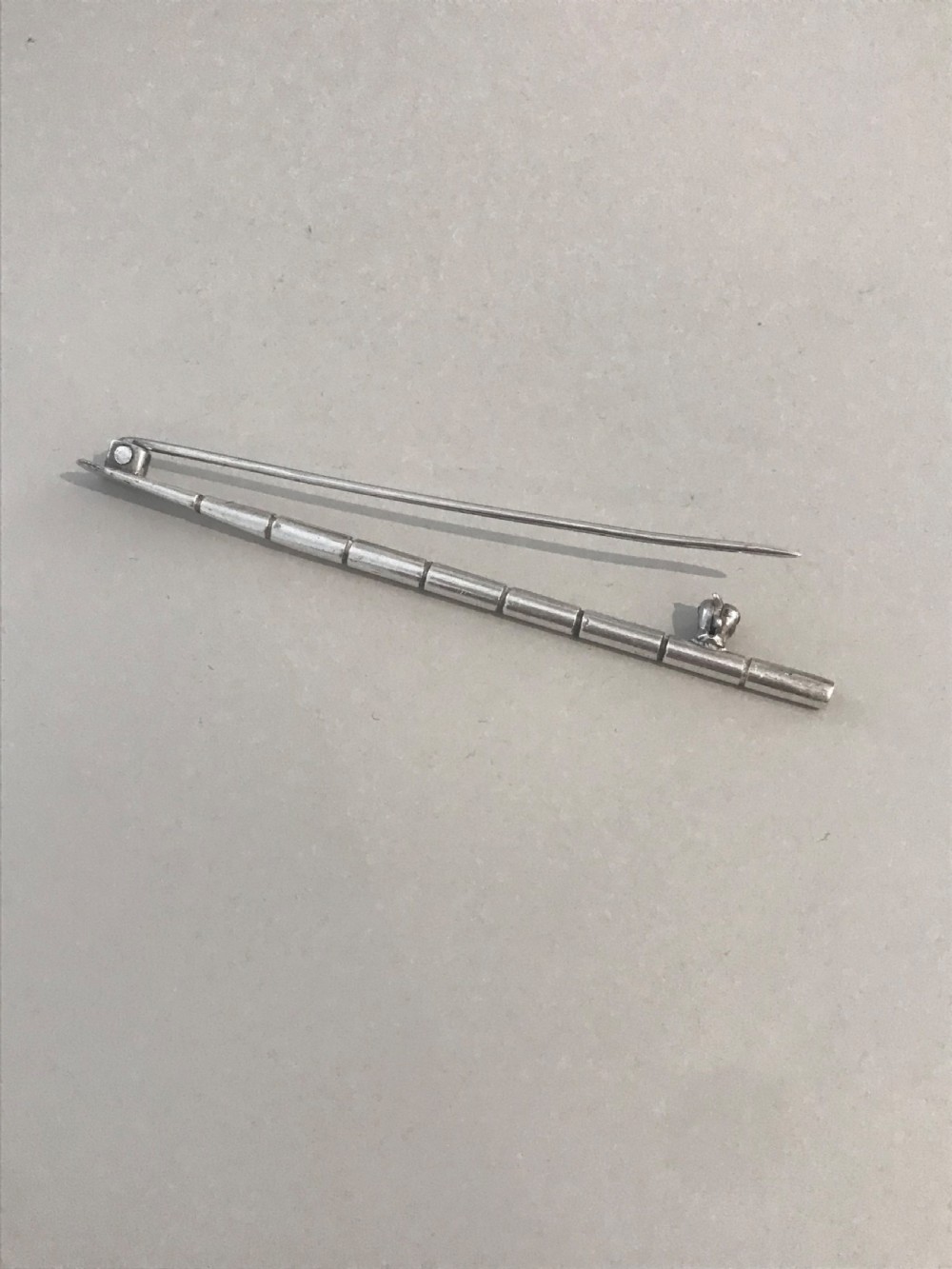 A silver brooch styled in the form of a rowing oar with a flat blade and segmented shaft. View VI