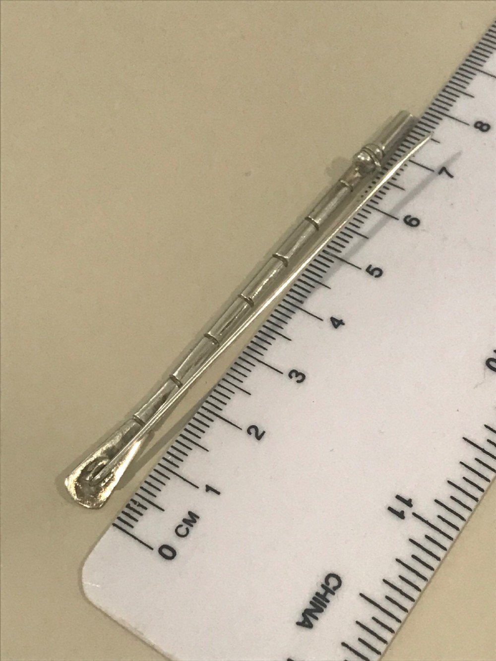 A silver brooch styled in the form of a rowing oar with a flat blade and segmented shaft. View VIII