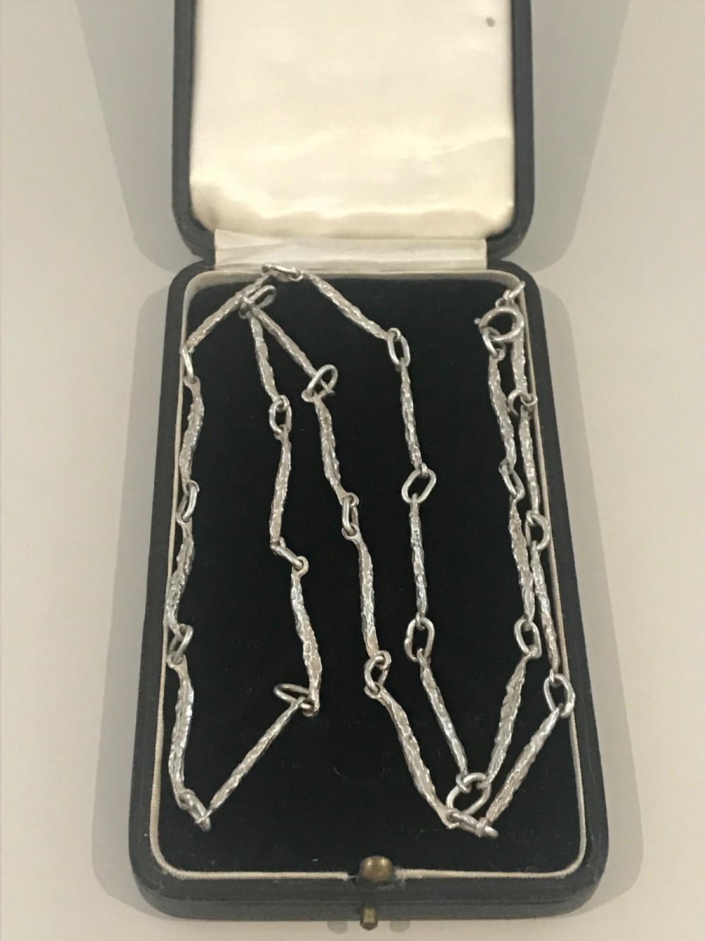 A vintage sterling silver chain necklace with elongated textured bar links presented inside a dark velvet-lined display box.