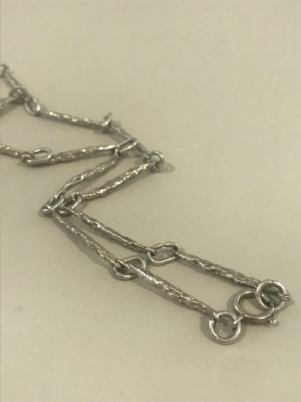 A vintage sterling silver chain necklace with elongated textured bar links presented inside a dark velvet-lined display box. View III