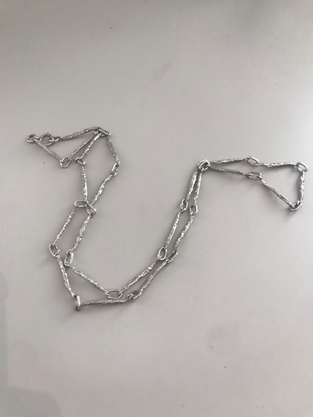 A vintage sterling silver chain necklace with elongated textured bar links presented inside a dark velvet-lined display box. View V