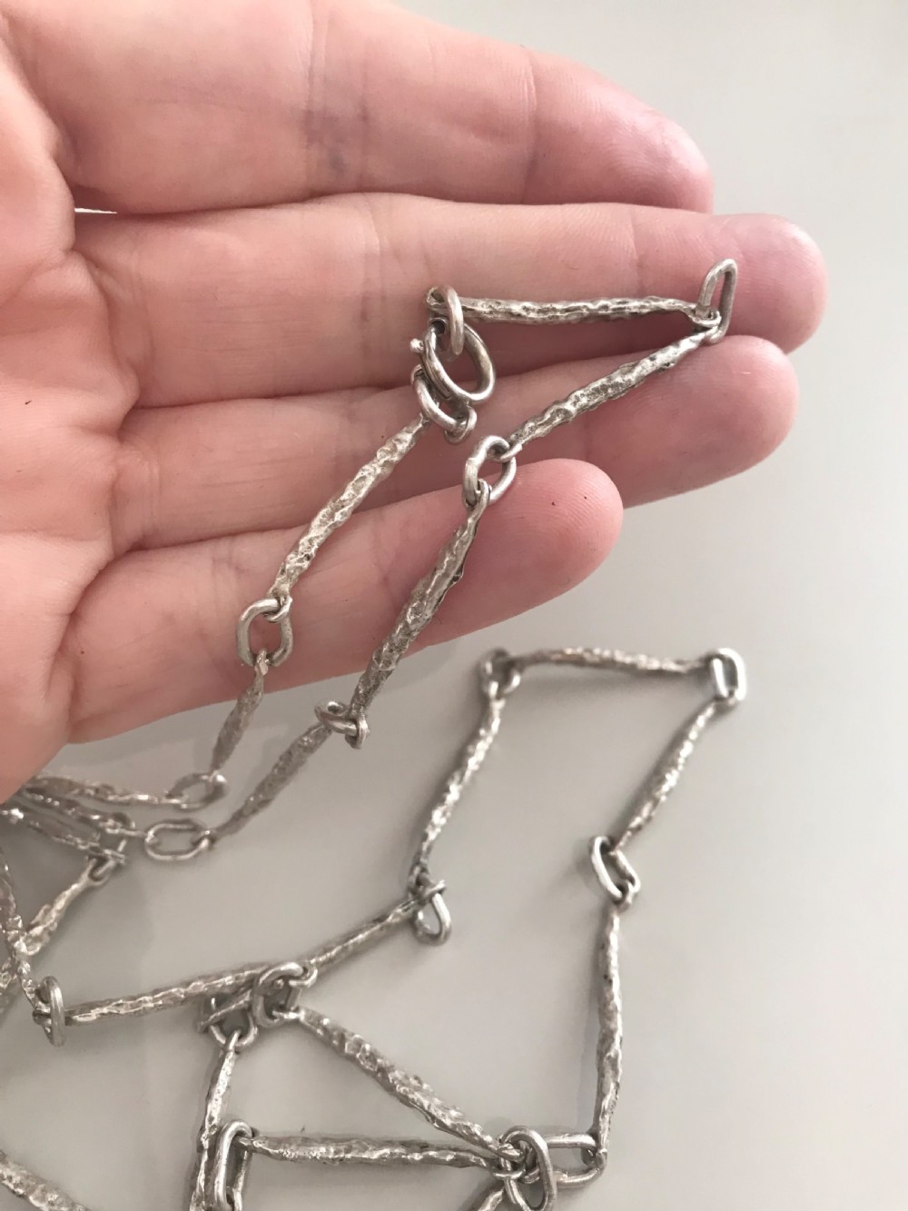 A vintage sterling silver chain necklace with elongated textured bar links presented inside a dark velvet-lined display box. View VI